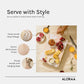 Hand carved wooden chopping board with floral design and rustic white wash finish used as a cheese platter with snacks